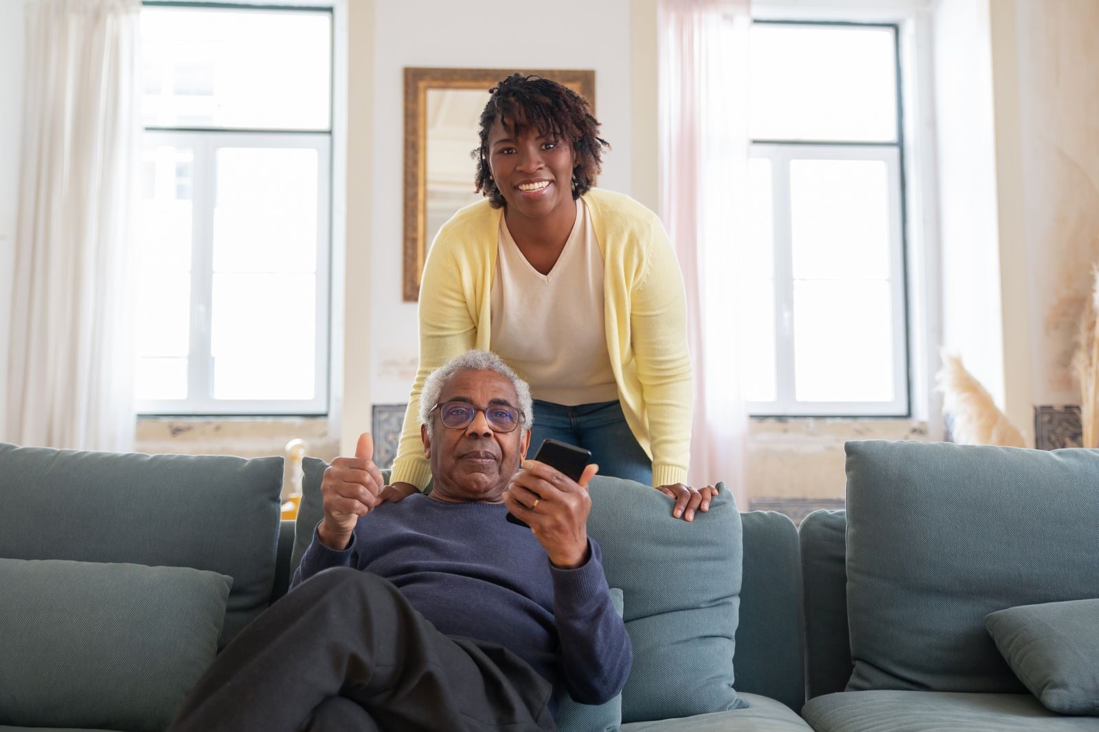 A caregiver and an older woman laughing together at home